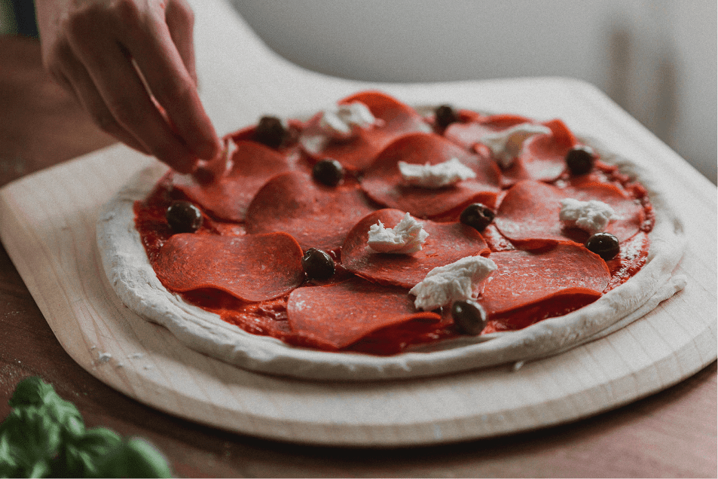 Adding toppings to Holy Napoli frozen pizza